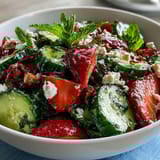 A vibrant spring salad with crisp cucumber, juicy strawberries, and fresh mint leaves, tossed with lemon-honey dressing.