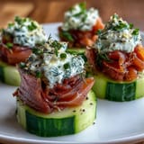 Elegant smoked salmon and cream cheese cucumber appetizers garnished with lemon zest and chives.