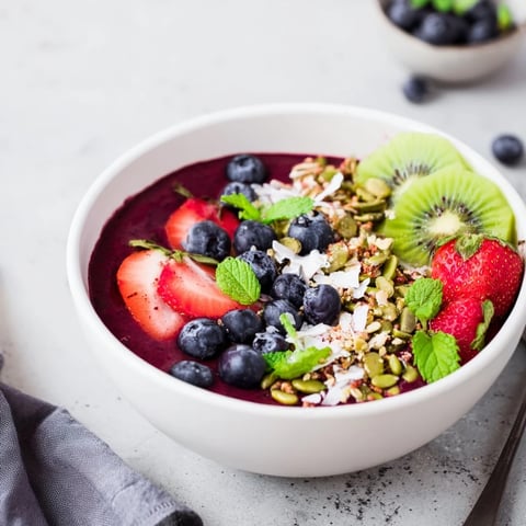 The vibrant purple Beet and Berry Smoothie Bowl topped with fresh kiwi slices and crunchy granola.