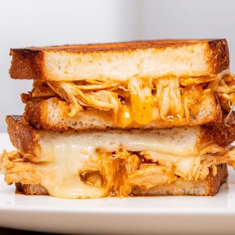 Crispy sourdough and gooey, spicy chicken filling this Chili Crisp Honey Chicken Grilled Cheese looks delicious.