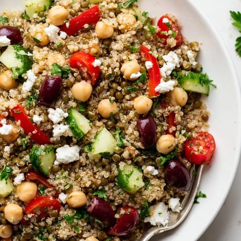 A vibrant bowl of Greek Power Salad with chickpeas, quinoa, and fresh chopped parsley.