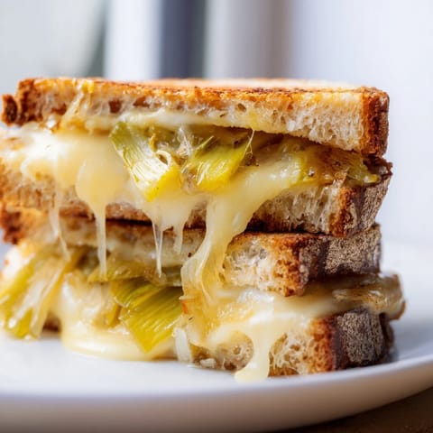 The sandwich is cut diagonally, revealing creamy melted Havarti and tender caramelized leeks inside.