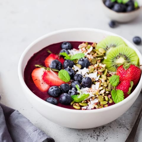 The vibrant purple Beet and Berry Smoothie Bowl topped with fresh kiwi slices and crunchy granola.