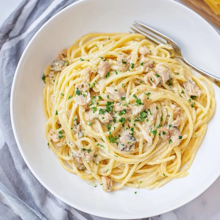 This Simple Garlic Butter Bucatini recipe shows tender shredded chicken atop perfectly cooked pasta; a comforting meal.
